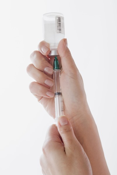 Close up of doctor's hand preparing syringe for injection. Photo : Rob Lewine
