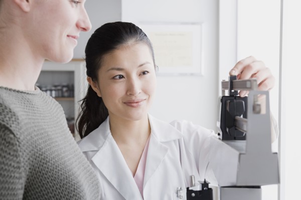 Close up of female doctor measuring woman's weight. Photo: Rob Lewine