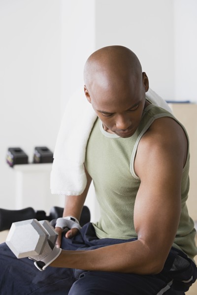 Young man lifting weights in gym. Photo : Rob Lewine