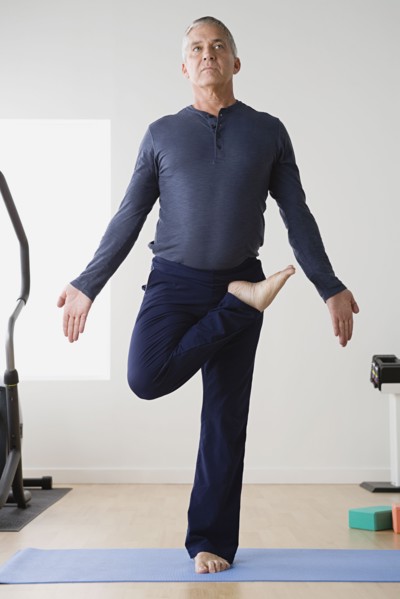 Mature man practicing yoga on mat. Photo : Rob Lewine