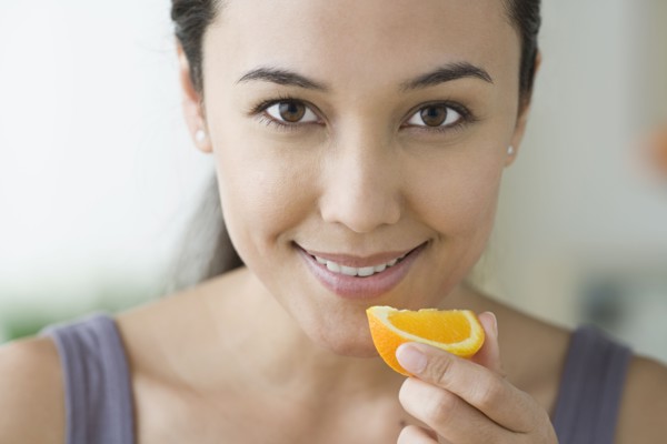 Portrait of attractive woman holding slice of orange. Photo : Rob Lewine