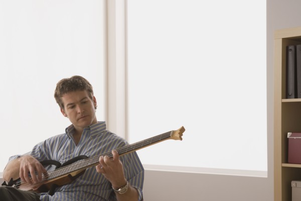 Young man playing electric base guitar. Photo : Rob Lewine