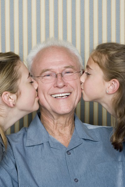 Portrait of two girls (8-9, 14-15) kissing grandfather. Photo : Rob Lewine