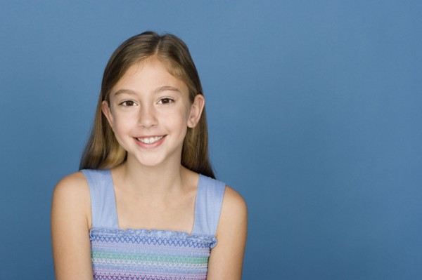 Portrait of happy girl (8-9) n blue background. Photo : Rob Lewine