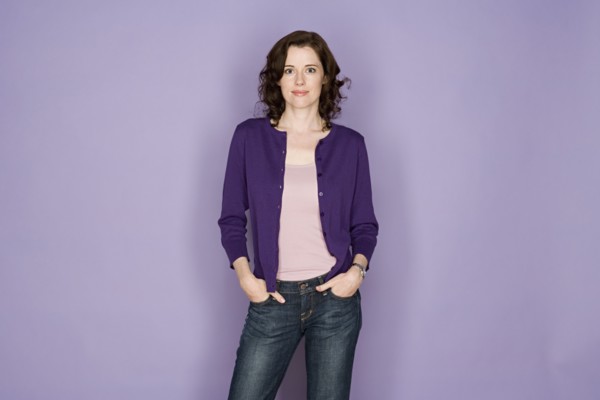 Portrait of smiling woman on purple background, studio shot. Photo : Rob Lewine