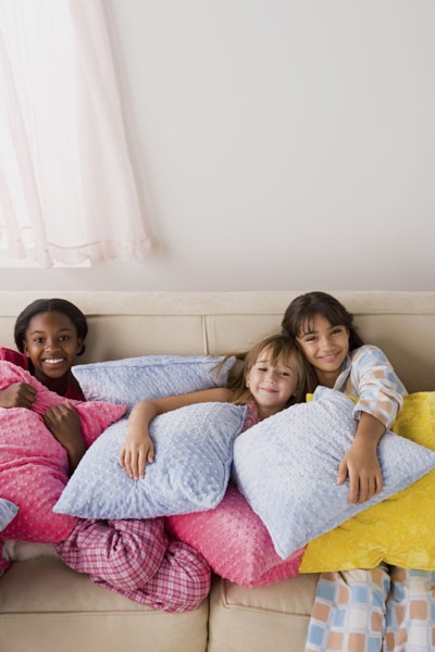 Portrait of three girls (10-11) lying on sofa at slumber party. Photo : Rob Lewine