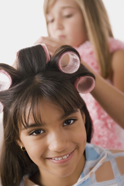 Portrait of girl (10-11) with curlers and another girl (10-11) in background. Photo : Rob Lewine