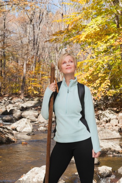 Female hiker standing by stream in forest. Photo: Tetra Images