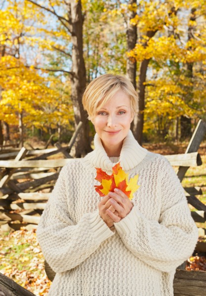 Portrait of smiling woman holding leaves in Autumn forest. Photo: Tetra Images