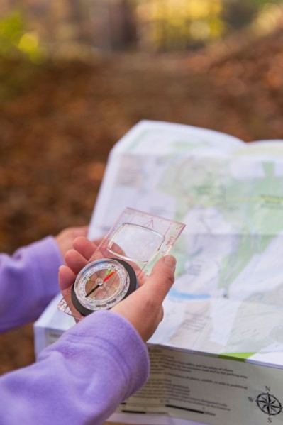 USA, New Jersey, Close-up of woman's hands holding compass and map. Photo : Tetra Images
