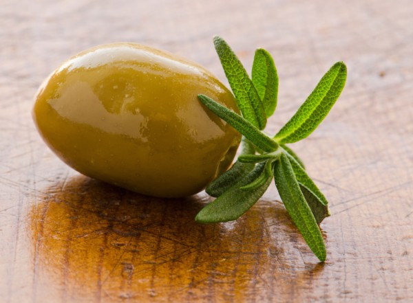 Close-up of green olive with rosemary, studio shot.
