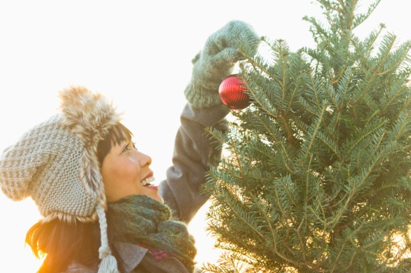 Smiling woman decorating Christmas tree.
