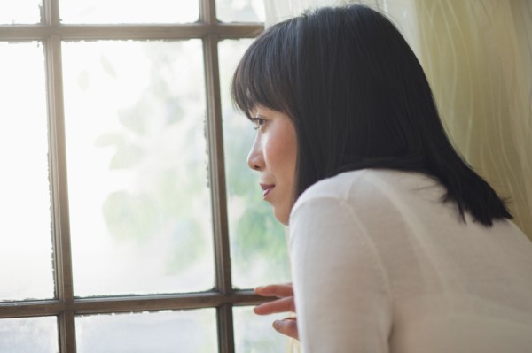 Thoughtful woman looking through window.