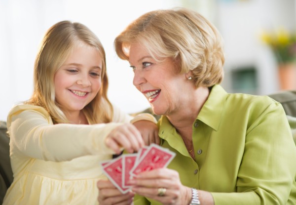 Grandmother with granddaughter (8-9) playing cards.