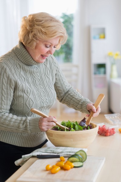Senior woman preparing salad .