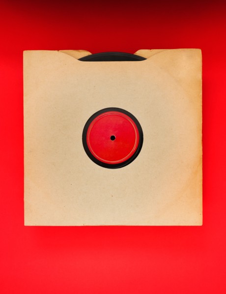 Vinyl record in envelope on red background, studio shot.