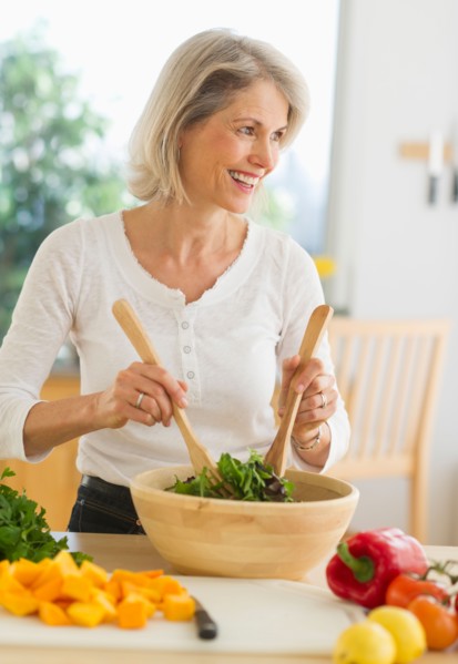 JPortrait of senior woman preparing salad in kitchen.