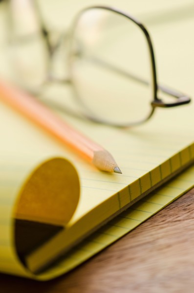 Close up of glasses, notebook and pencil, studio shot.