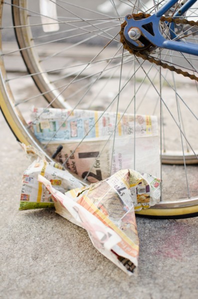USA, New York State, New York City, Crumpled newspaper under bicycle wheel. Photo : Jamie Grill