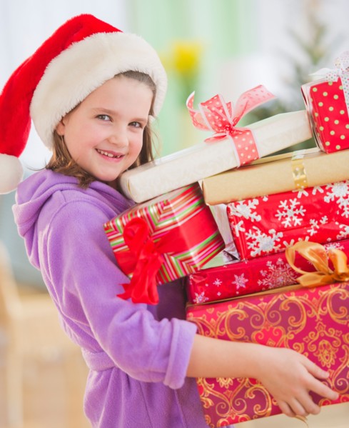 Girl (8-9) carrying christmas gifts. Photo : Daniel Grill