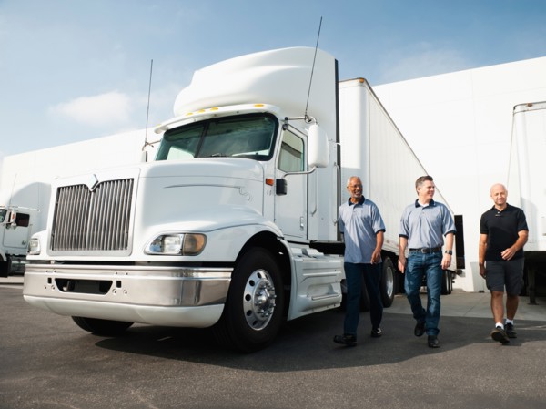 Three men walking between trucks.