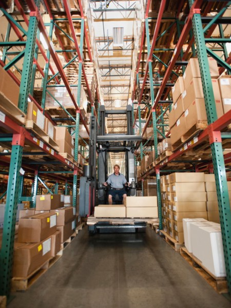 Forklift truck stacking boxes in warehouse.