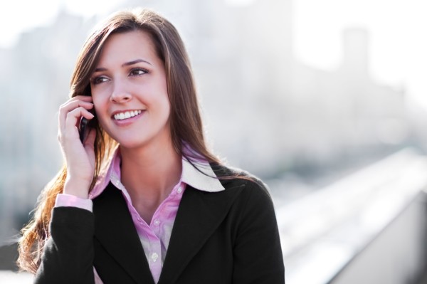 Smiling young businesswoman talking via mobile. Photo : Take A Pix Media