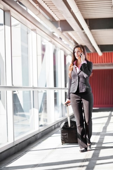 Smiling businesswoman walking with suitcase. Photo : Take A Pix Media