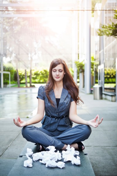 USA, Seattle, Young businesswoman meditating in front of crumbled paper balls. Photo : Take A Pix