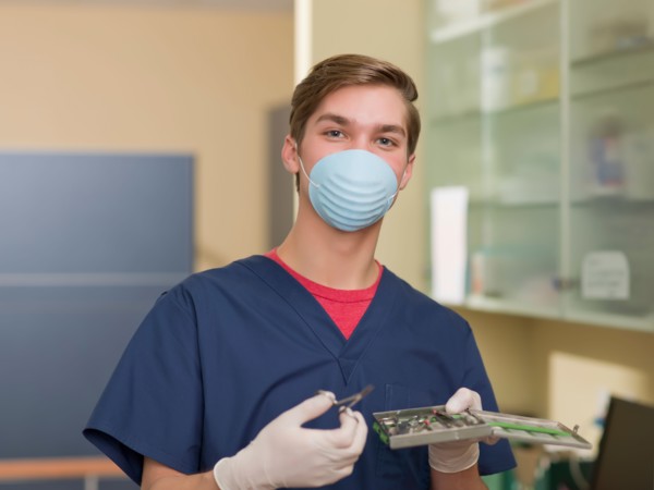 Portrait of dentist holding dental tools. Photo : Dan Bannister