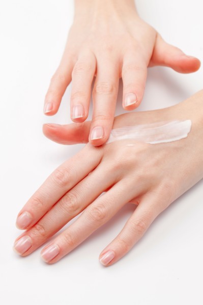 Close up of woman's hands applying moisturizer, studio shot. Photo : Jan Scherders