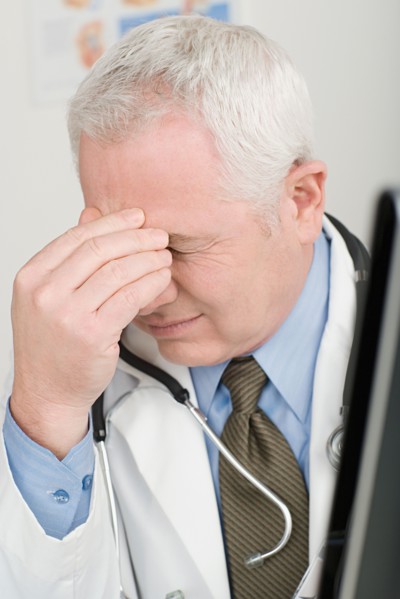 Doctor rubbing forehead. Photo : Rob Lewine