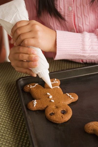 Teenage girl (16-17) decorating gingerbread with icing. Photo : Rob Lewine