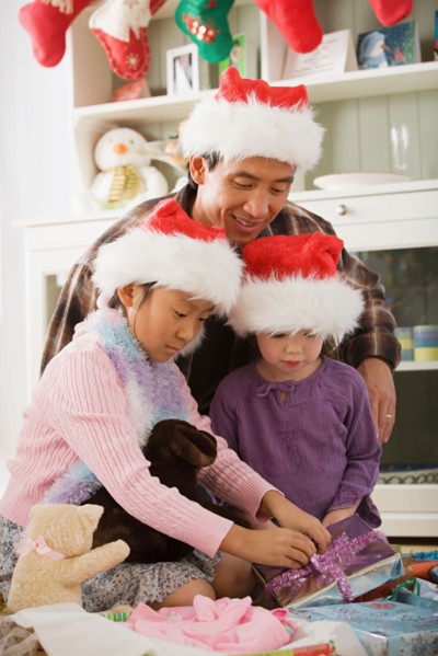 Father and daughters (10-11) unwrapping christmas gifts. Photo : Rob Lewine