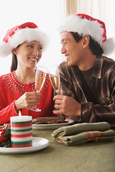 Couple wearing santa hats toasting with champagne. Photo : Rob Lewine