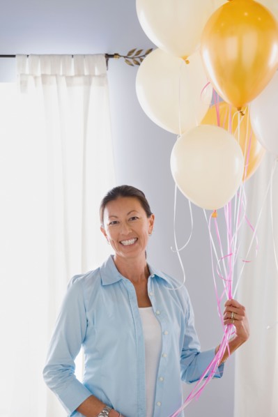 Portrait of mature woman with balloons. Photo : Rob Lewine