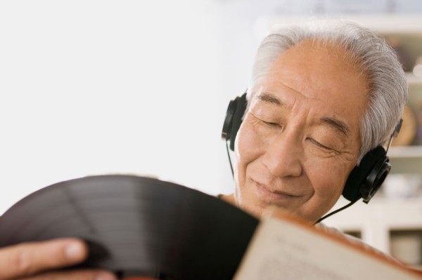 Senior man listening to vinyl record. Photo : Rob Lewine