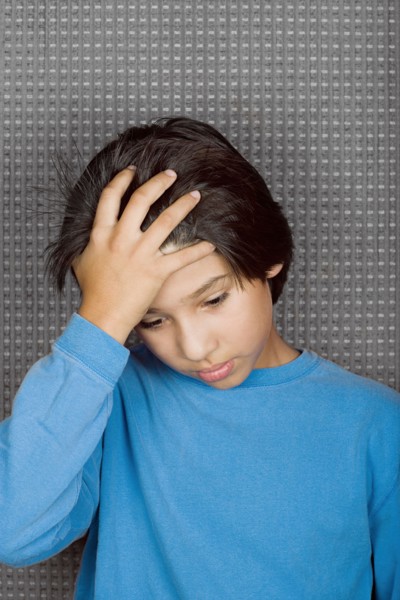 Studio portrait of boy with hand on forehead. Photo : Rob Lewine