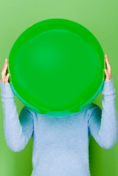 Studio shot portrait of teenage girl holding ball in front of her face, waist up. Photo : Rob