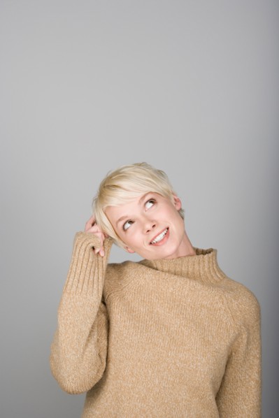 Studio shot portrait of young woman scratching head, waist up. Photo : Rob Lewine