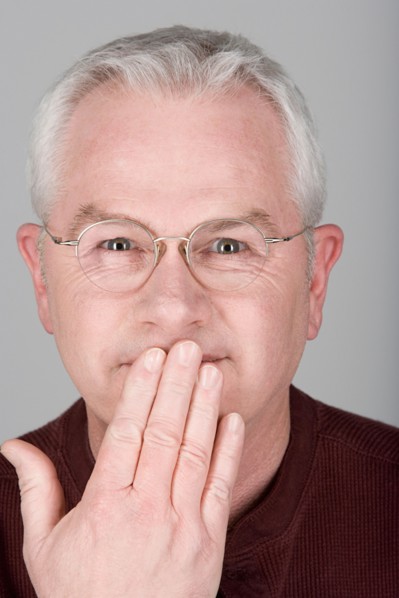 Studio shot portrait of senior man with hand covering mouth, close-up. Photo : Rob Lewine