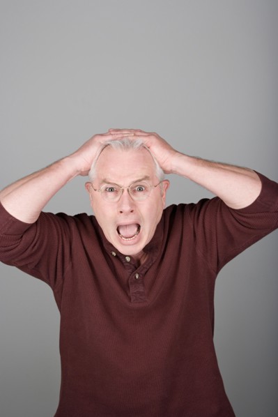 Studio shot portrait of senior man with head in hands and open mouth, waist up. Photo : Rob Lewine