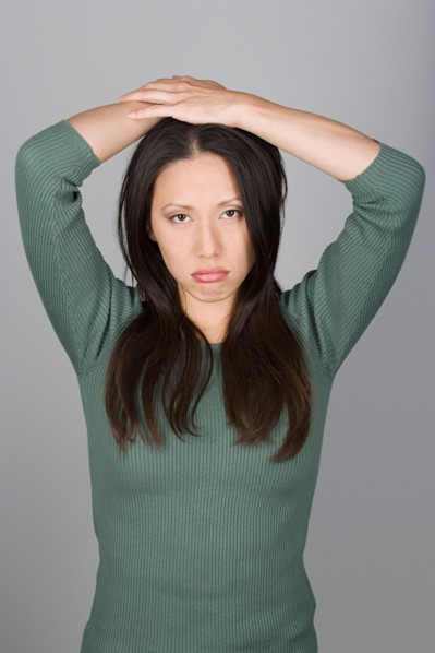 Studio shot portrait of mid adult woman with arms raised, waist up. Photo : Rob Lewine