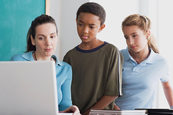 Boy and girl with teacher using laptop . Photo : Rob Lewine