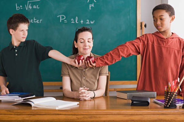 Two boys holding apples in front of teacher. Photo : Rob Lewine