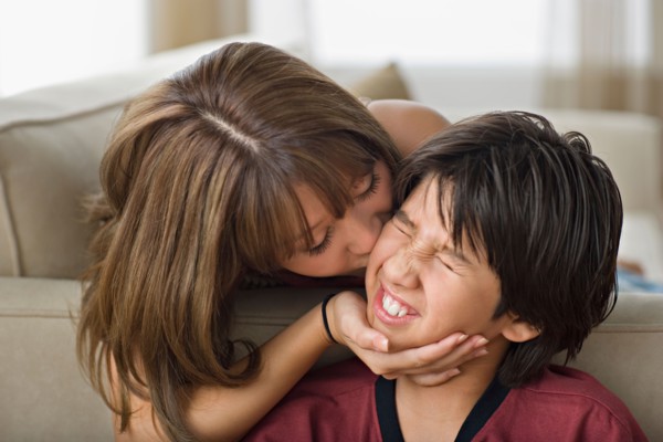 Sister kissing younger brother. Photo : Rob Lewine