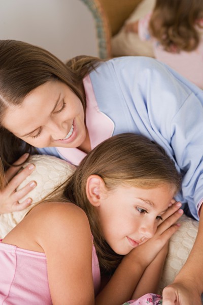 Mother lying in bed with daughter (12-13) . Photo : Rob Lewine