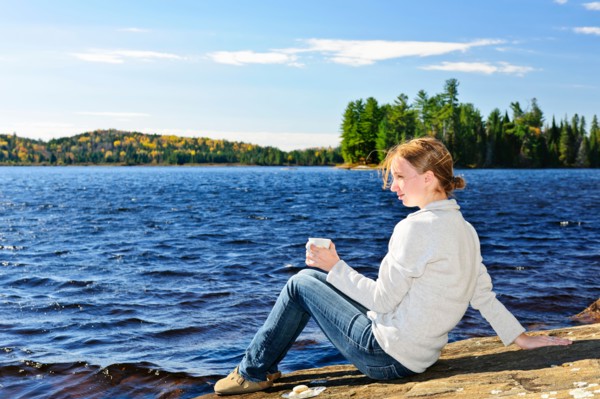 Canada, Ontario, Algonquin Park, Teenage girl sitting on rock and looking at lake. Photo :  Elena