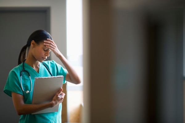 Female nurse with head in hands.