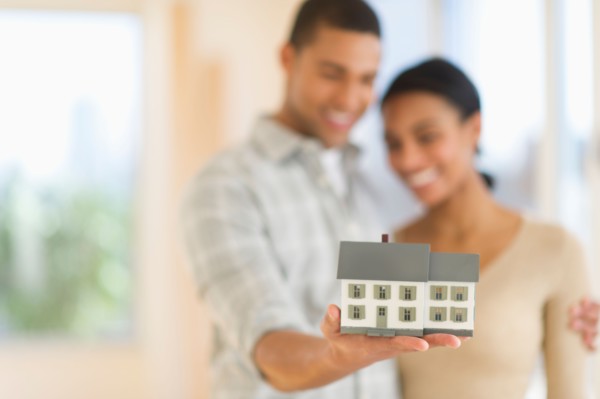 Couple holding toy house.